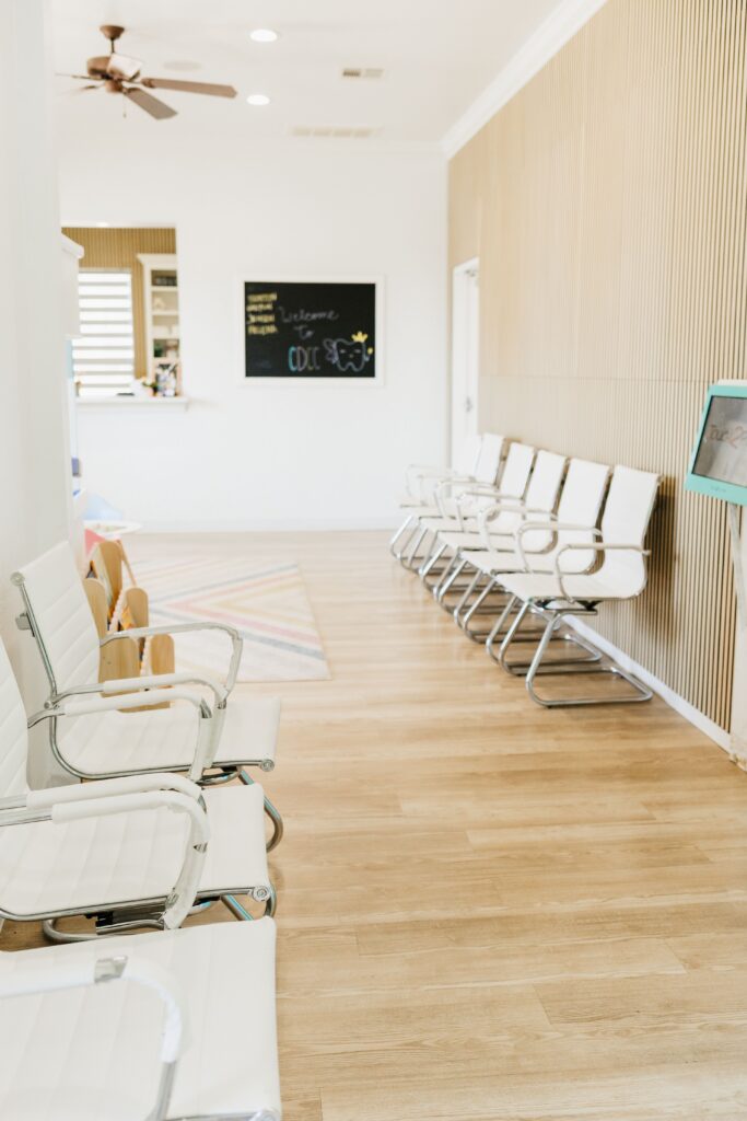 A modern, light-filled waiting room with rows of white chairs, wood floors, and a "Welcome to CDCC" chalkboard.